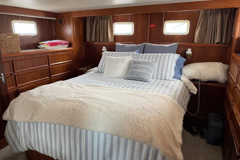 Slide: The Image of Cozy bedroom interior of 1981 Hatteras 43 Motor Yacht with wood paneling and striped bedding. - 48