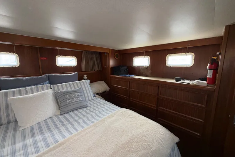 Slide: The Image of Cozy bedroom interior of 1981 Hatteras 43 Motor Yacht with striped bedding and wooden cabinetry. - 49