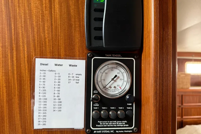 Slide: The Image of 1981 Hatteras 43 Motor Yacht tank tender gauge and fuel capacity chart on wooden panel. - 59
