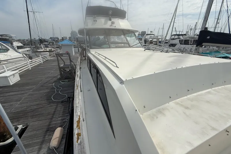 Slide: The Image of 1981 Hatteras 43 Motor Yacht docked at marina, showcasing sleek design and spacious deck. - 12
