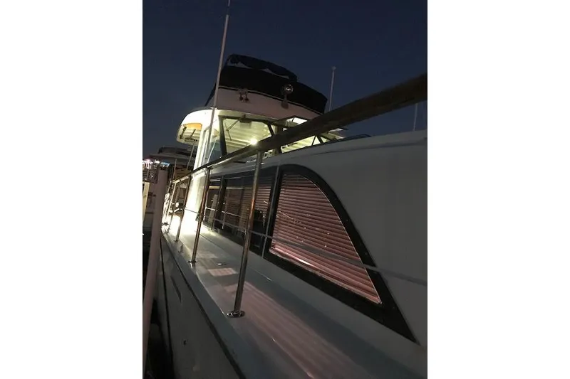 Slide: The Image of 1981 Hatteras 43 Motor Yacht illuminated at night, docked with visible railings and windows. - 6