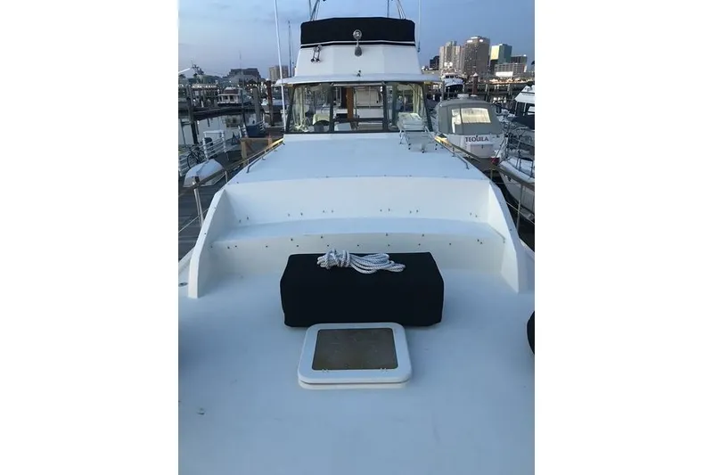 Slide: The Image of 1981 Hatteras 43 Motor Yacht docked at marina, showcasing spacious deck and city skyline. - 20