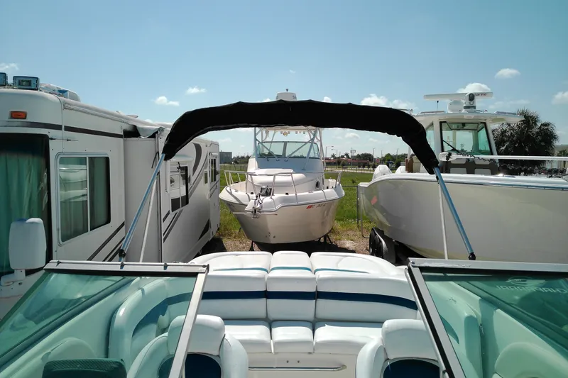 Slide: The Image of 2006 Chaparral 236 SSi boat parked between RVs and other boats under a clear sky. - 17
