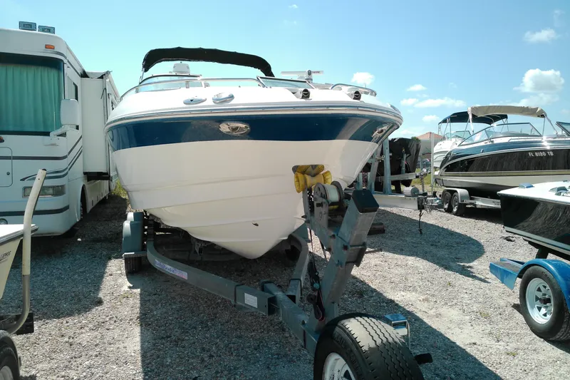 Slide: The Image of 2006 Chaparral 236 SSi boat on trailer, parked beside RV under clear blue sky. - 18