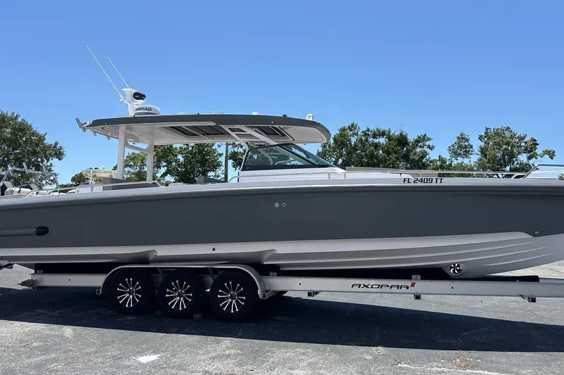 The Image of 2024 Axopar 37 Sun-Top boat on trailer, side view, clear sky background. - 1