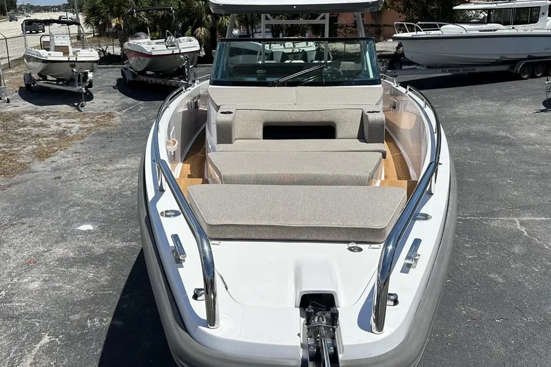 Slide: The Image of 2024 Axopar 37 Sun-Top boat with cushioned seating, docked outdoors. - 12