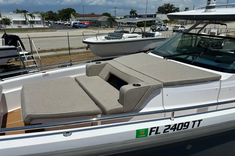Slide: The Image of 2024 Axopar 37 Sun-Top boat with cushioned sunbathing area, docked in a marina. - 13