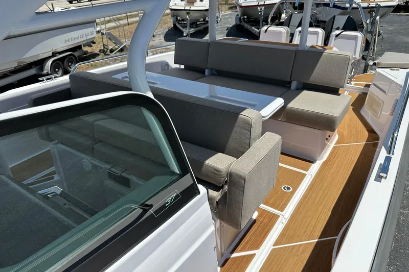 Slide: The Image of 2024 Axopar 37 Sun-Top boat interior with cushioned seating and wooden deck. - 21