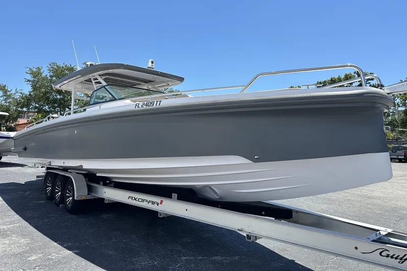 Slide: The Image of 2024 Axopar 37 Sun-Top boat on trailer, sleek design, parked outdoors. - 3