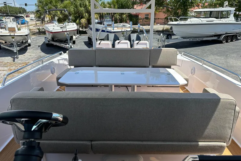 Slide: The Image of 2024 Axopar 37 Sun-Top boat interior with seating and table, parked among other boats. - 33