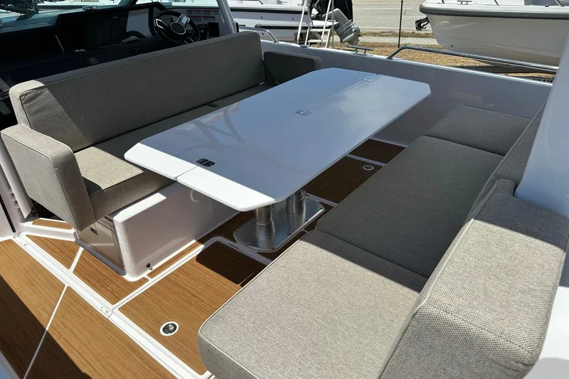 Slide: The Image of 2024 Axopar 37 Sun-Top boat interior with cushioned seating and sleek table design. - 34