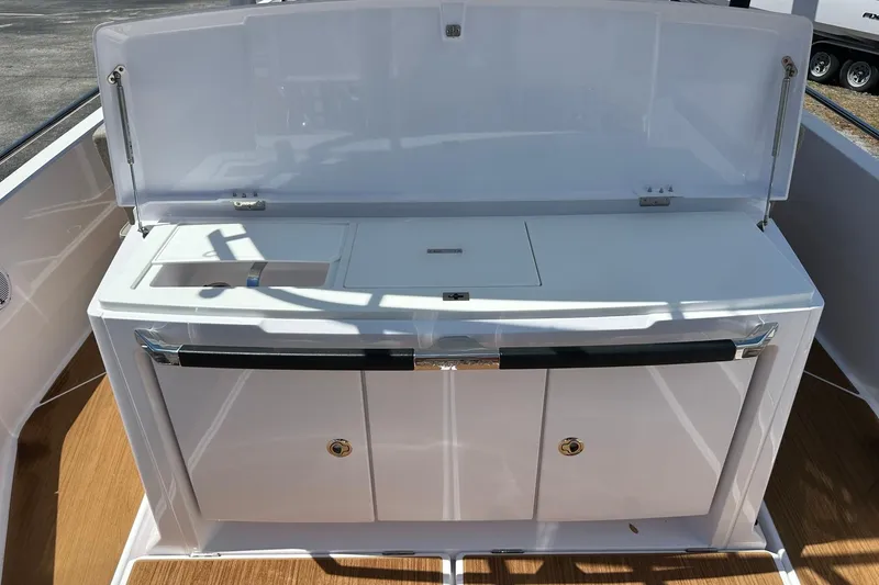 Slide: The Image of 2024 Axopar 37 Sun-Top boat interior with sleek white cabinetry and wood flooring. - 43