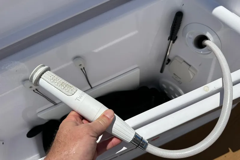 Slide: The Image of Hand holding a white shower hose in an Axopar 37 Sun-Top boat, 2024 model. - 46
