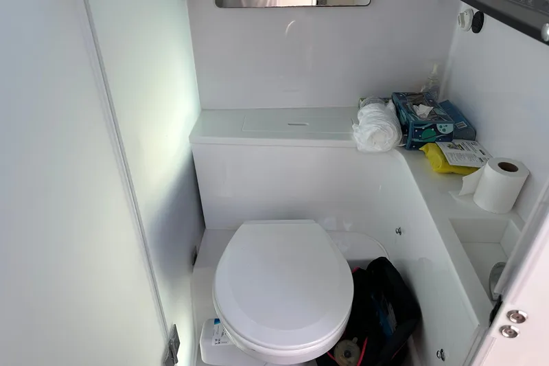 Slide: The Image of 2024 Axopar 37 Sun-Top boat bathroom with toilet, storage, and toiletries. - 50
