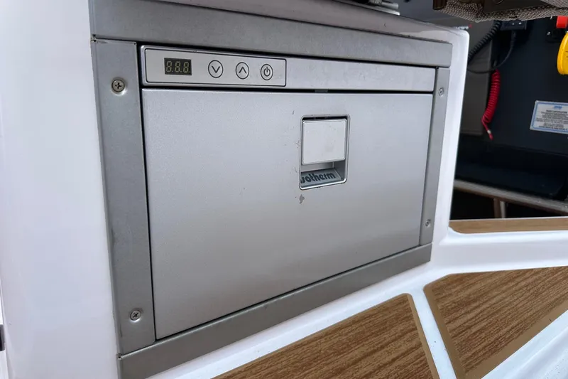 Slide: The Image of 2024 Axopar 37 Sun-Top boat interior with built-in fridge and control panel. - 61