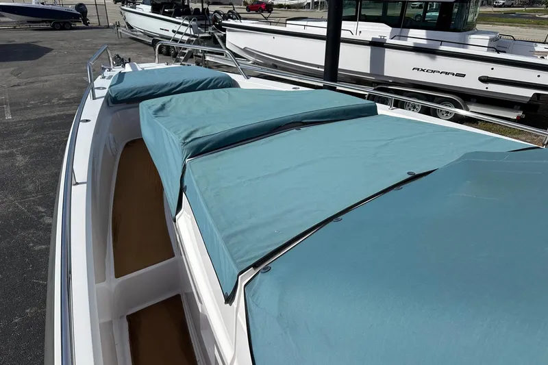 Slide: The Image of 2024 Axopar 37 Sun-Top boat with teal cushions, docked at a marina. - 67