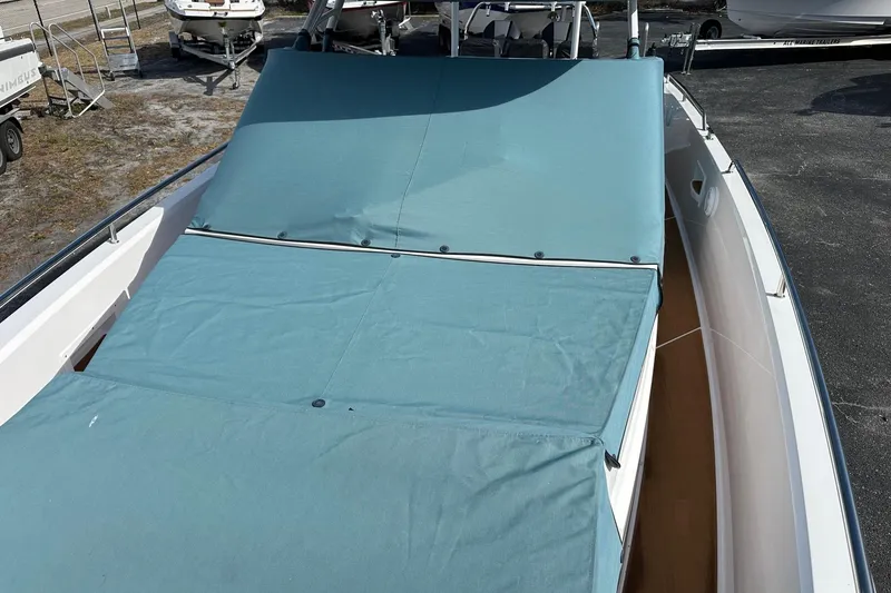 Slide: The Image of 2024 Axopar 37 Sun-Top boat with blue cover, docked outdoors. - 68