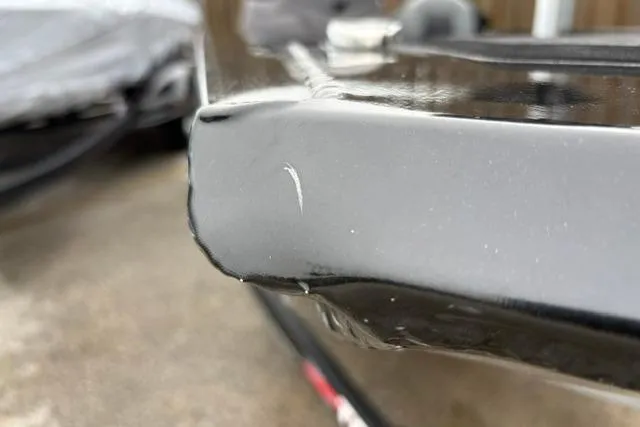 Slide: The Image of Close-up of a 2023 Tracker Pro 170 boat with a small scratch on the black surface. - 14