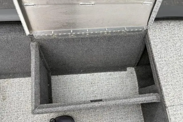 Slide: The Image of Open storage compartment in 2023 Tracker Pro 170 boat, featuring gray carpeted interior. - 18
