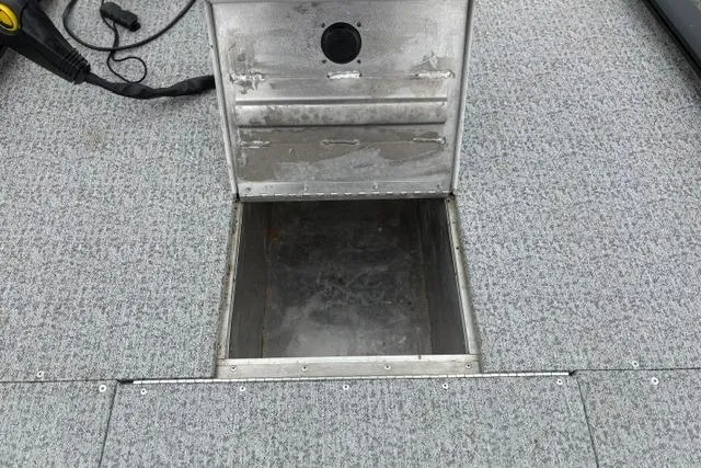 Slide: The Image of 2023 Tracker Pro 170 boat storage compartment with open hatch on carpeted deck. - 30