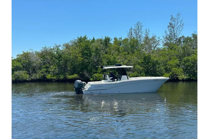 Slide: The Image of 2023 World Cat 280 CC-X boat cruising on a calm river with lush greenery. - 11