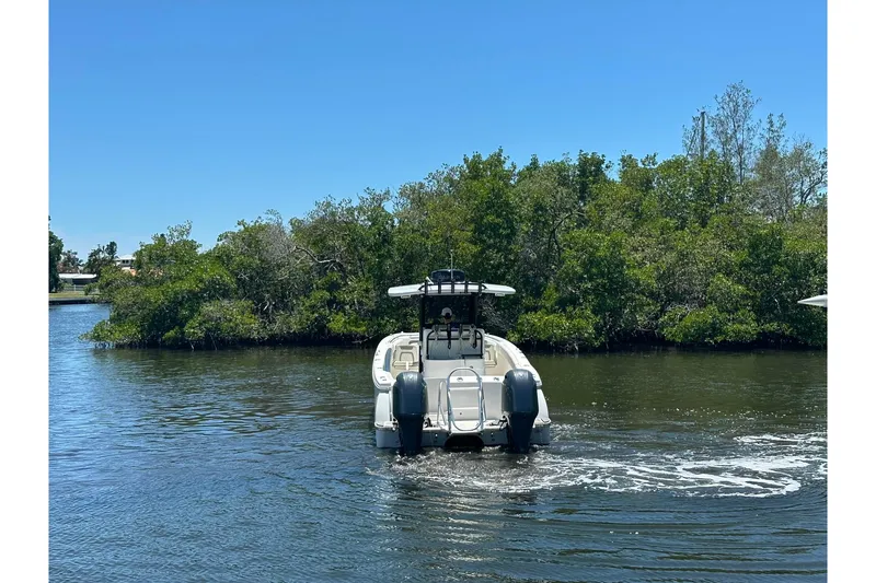 Slide: The Image of 2023 World Cat 280 CC-X boat cruising on a calm river with lush greenery. - 13