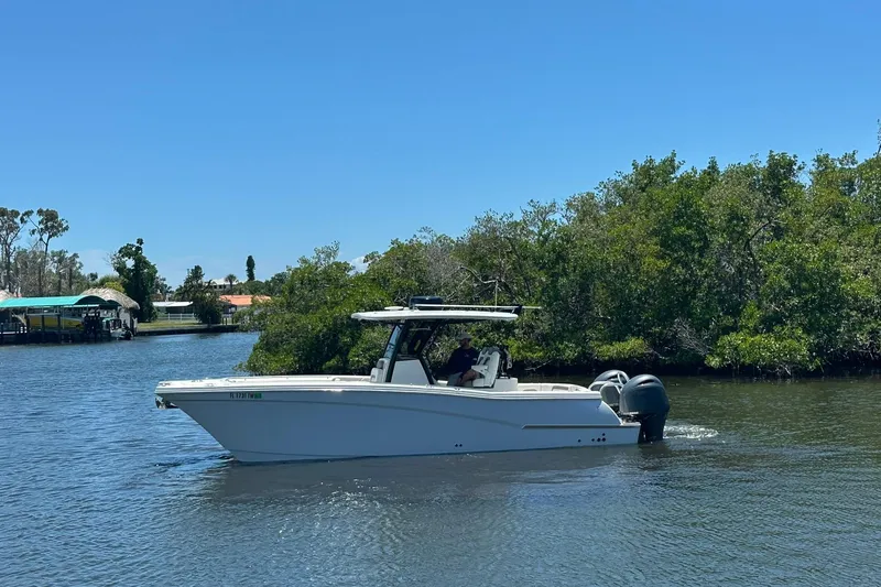 The Image of 2023 World Cat 280 CC-X boat cruising on a sunny day near lush greenery. - 0