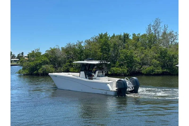 Slide: The Image of 2023 World Cat 280 CC-X boat cruising on a calm river with lush greenery. - 12