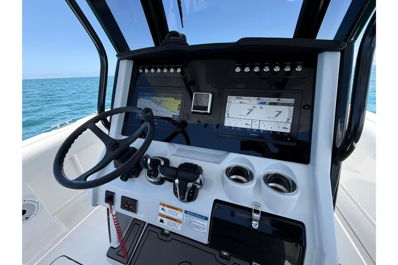 Slide: The Image of 2023 World Cat 280 CC-X boat dashboard with steering wheel and navigation screens. - 6