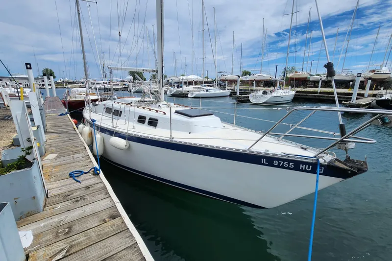 The Image of 1981 Columbia Yacht 10.7 docked at marina, surrounded by other boats under a cloudy sky. - 0