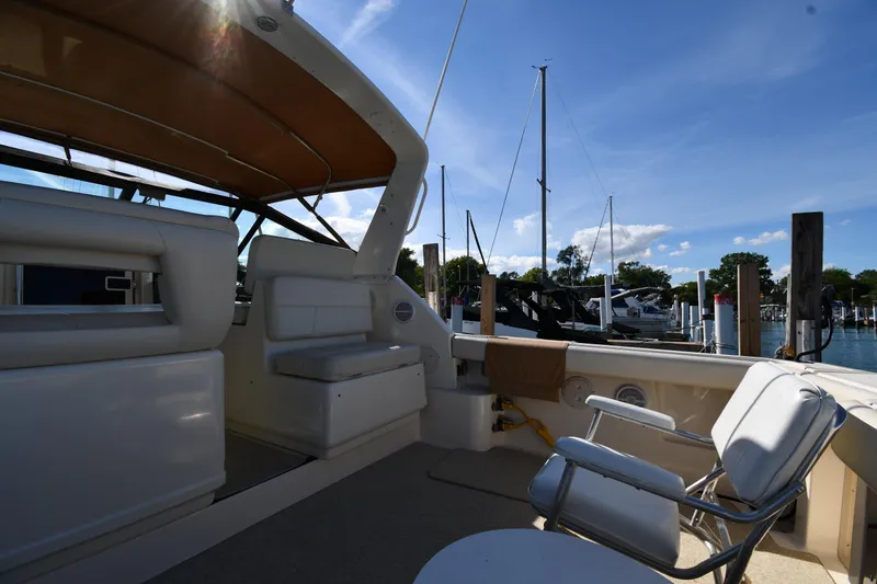 Slide: The Image of 1998 Tiara Yachts 3100 Open interior with seating, docked at marina under clear blue sky. - 15