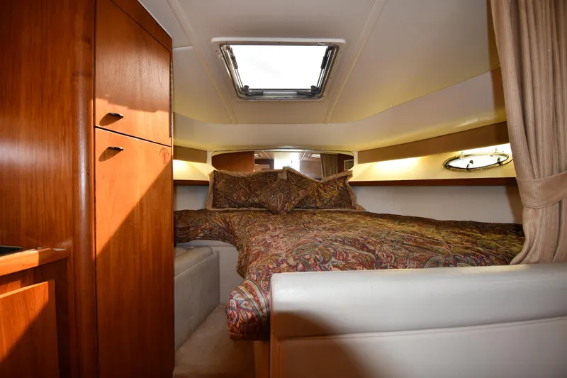 Slide: The Image of Cozy cabin interior of 1998 Tiara Yachts 3100 Open with wood cabinetry and patterned bedding. - 20