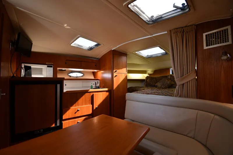 Slide: The Image of Interior of 1998 Tiara Yachts 3100 Open, featuring cozy cabin with kitchenette and seating area. - 24