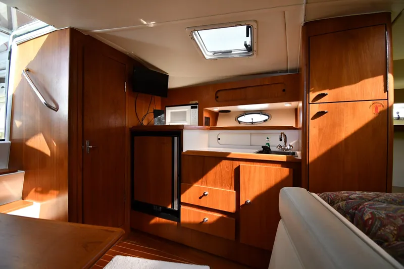 Slide: The Image of Interior of 1998 Tiara Yachts 3100 Open, featuring wooden cabinetry and compact kitchen amenities. - 25