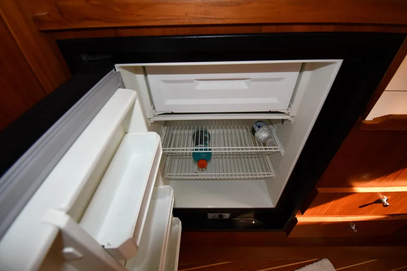 Slide: The Image of 1998 Tiara Yachts 3100 Open refrigerator with drinks inside, wooden cabinetry background. - 30