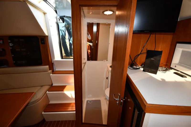 Slide: The Image of Interior of 1998 Tiara Yachts 3100 Open, featuring cabin seating, steps, and compact bathroom. - 31