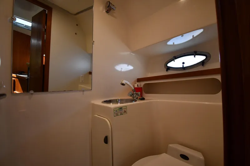 Slide: The Image of Bathroom interior of 1998 Tiara Yachts 3100 Open, featuring sink and porthole window. - 32