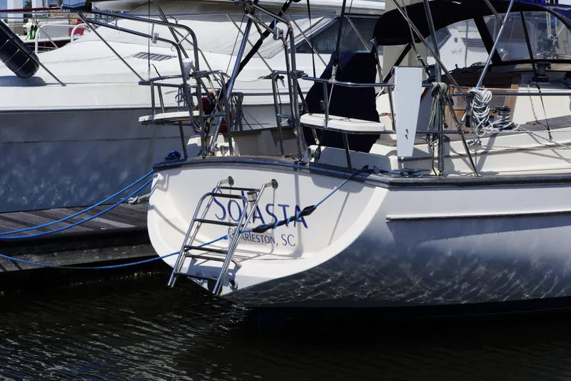 Slide: The Image of 1997 Island Packet 37 sailboat docked, featuring rear view with ladder and ropes. - 14