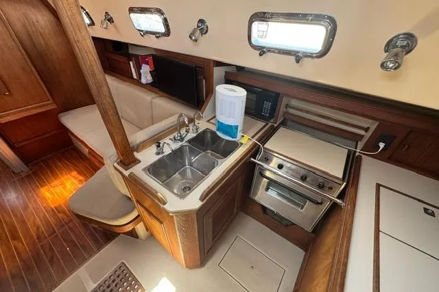 Slide: The Image of Interior of a 1997 Island Packet 37 sailboat featuring a compact kitchen area. - 16