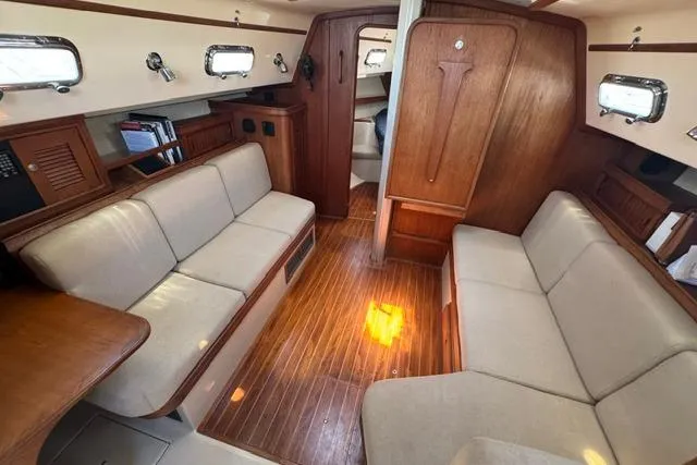 Slide: The Image of Interior of a 1997 Island Packet 37 sailboat with wooden flooring and beige seating. - 17