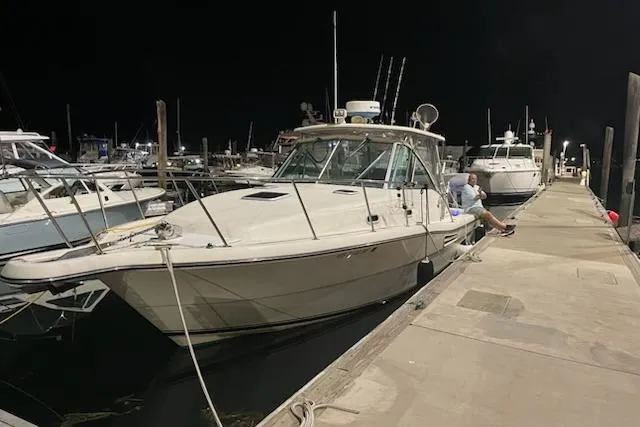Slide: The Image of 2003 Pursuit 3000 Express boat docked at night, surrounded by other vessels. - 12