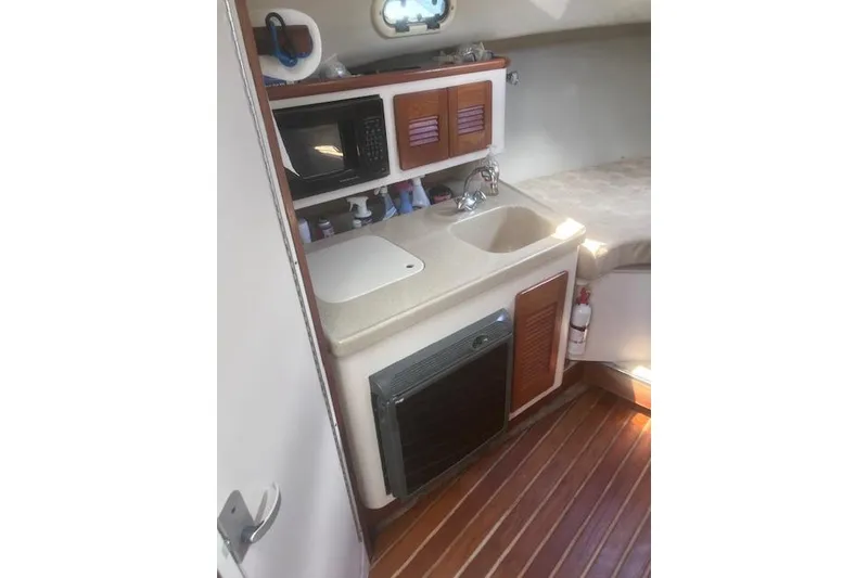Slide: The Image of 2003 Pursuit 3000 Express boat interior with kitchenette and wooden flooring. - 25