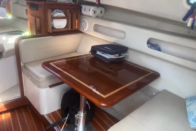 Slide: The Image of 2003 Pursuit 3000 Express cabin interior with wooden table and seating area. - 26