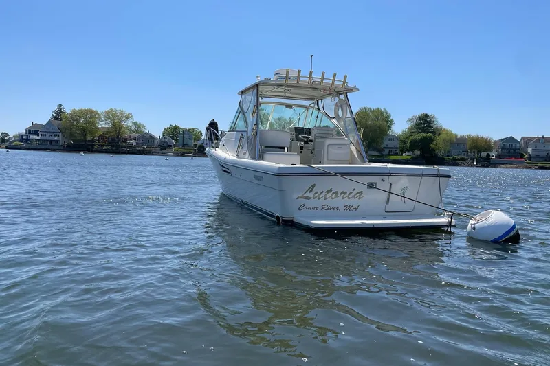 Slide: The Image of 2003 Pursuit 3000 Express boat on water near shoreline homes. - 4