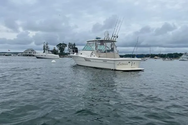 Slide: The Image of 2003 Pursuit 3000 Express boat anchored in a calm harbor under cloudy skies. - 5