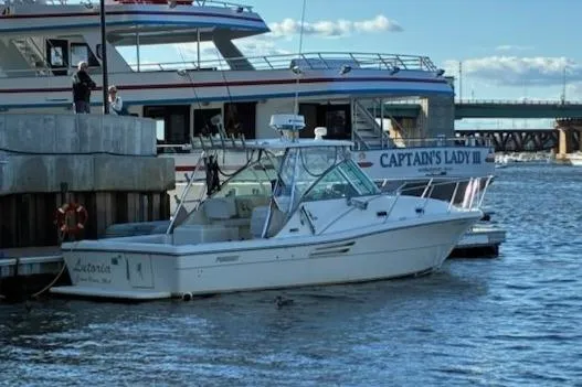 Slide: The Image of 2003 Pursuit 3000 Express boat docked near larger vessel, "Captain's Lady III," in a marina. - 6