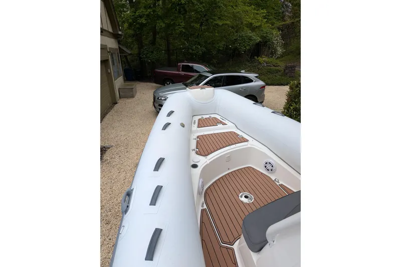Slide: The Image of 2016 Brig E780 inflatable boat with wooden deck, parked near cars in a driveway. - 12