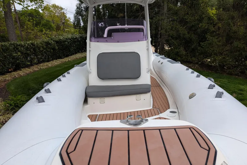 Slide: The Image of 2016 Brig E780 inflatable boat with cushioned seating and wooden deck, surrounded by greenery. - 13