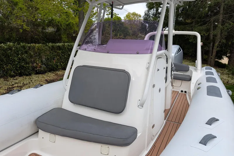 Slide: The Image of 2016 Brig E780 boat with cushioned seating and sleek design in a wooded setting. - 4