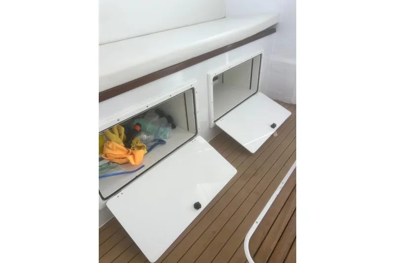 Slide: The Image of Storage compartments on a 1973 Bertram 31 Flybridge Cruiser with open hatches and cleaning supplies. - 34